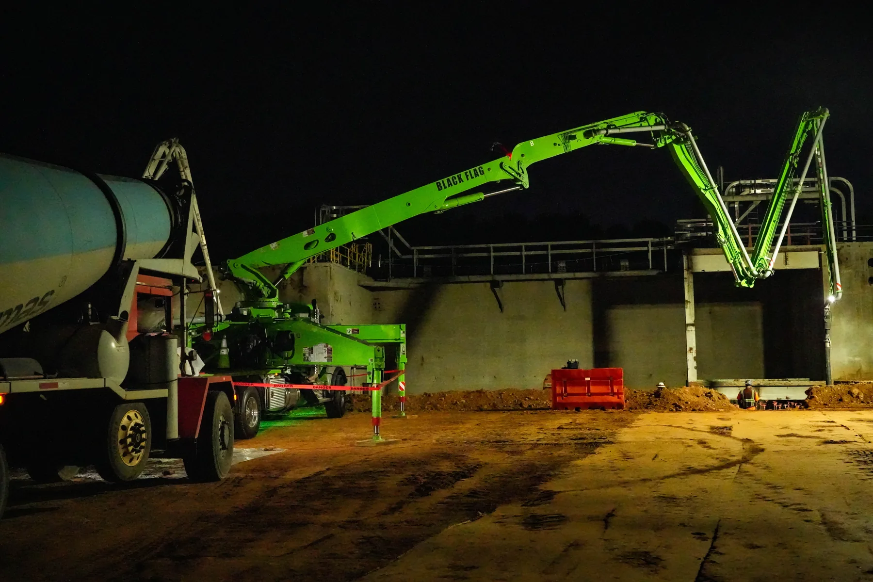 Black Flag Concrete Pumping boom pump illuminated at night
